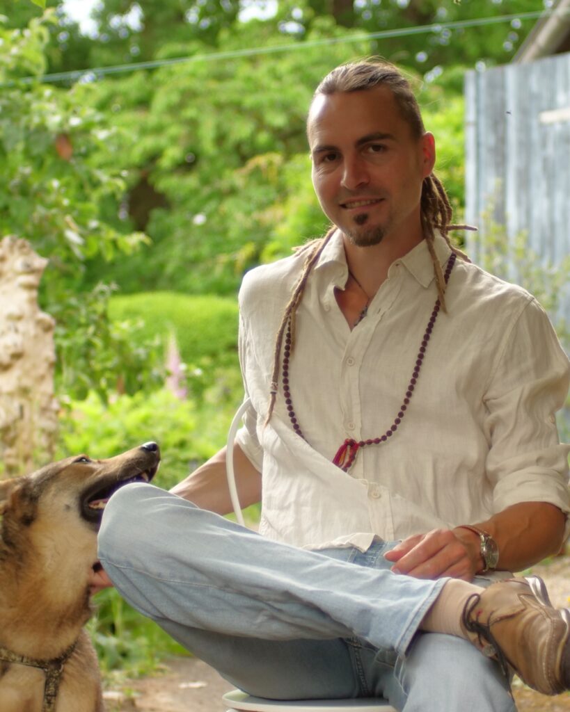 Malte Rödiger, freundlich lächelnd in einem Garten, krault seine Hündin Lana