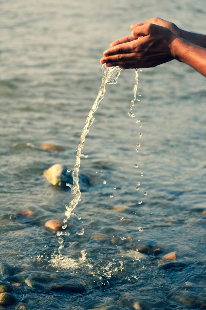 zwei Hände schöpfen Wasser, ein Symbol für Fluss, Klarheit und Reinigung